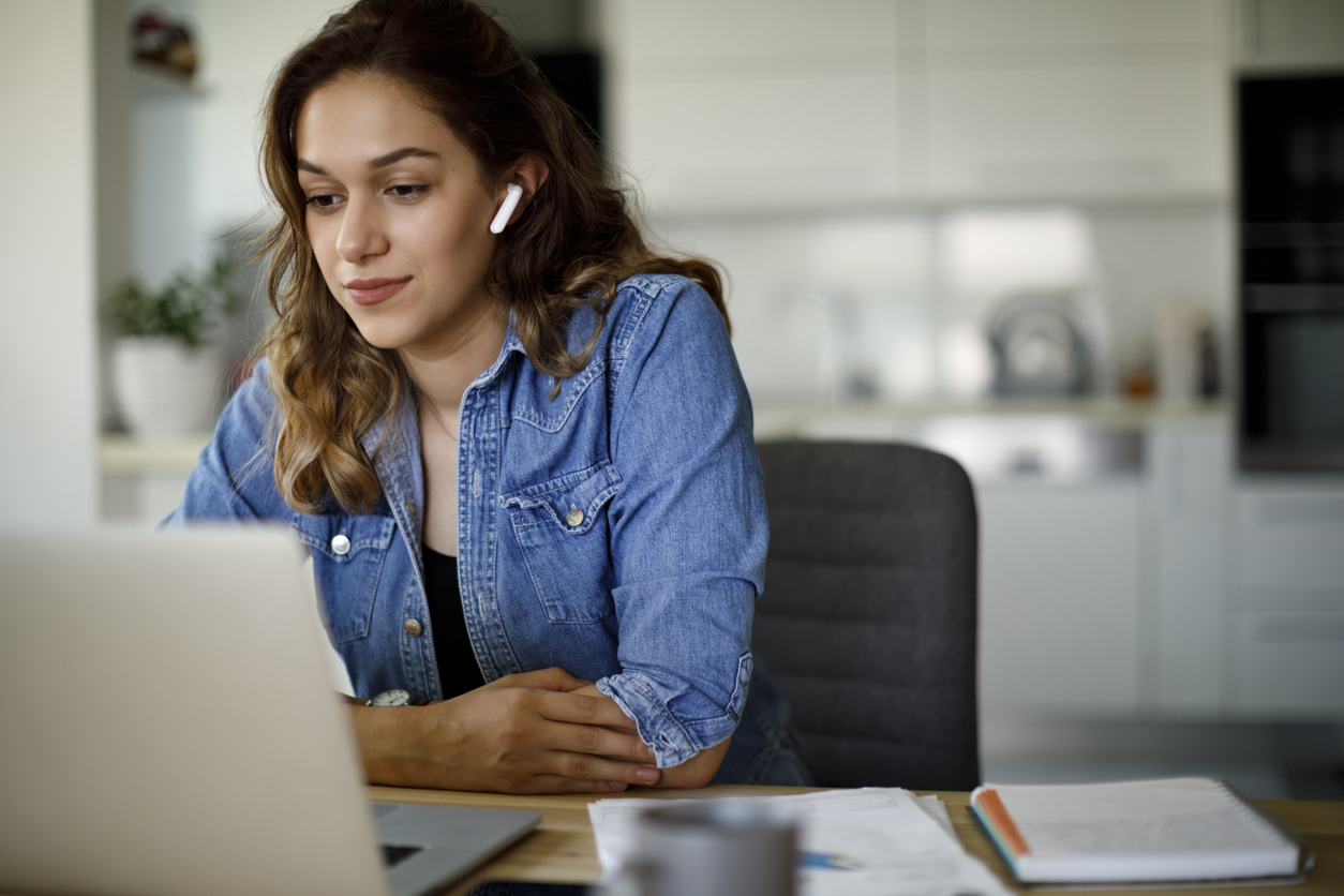 Young woman with bluetooth headphones having video conference at home