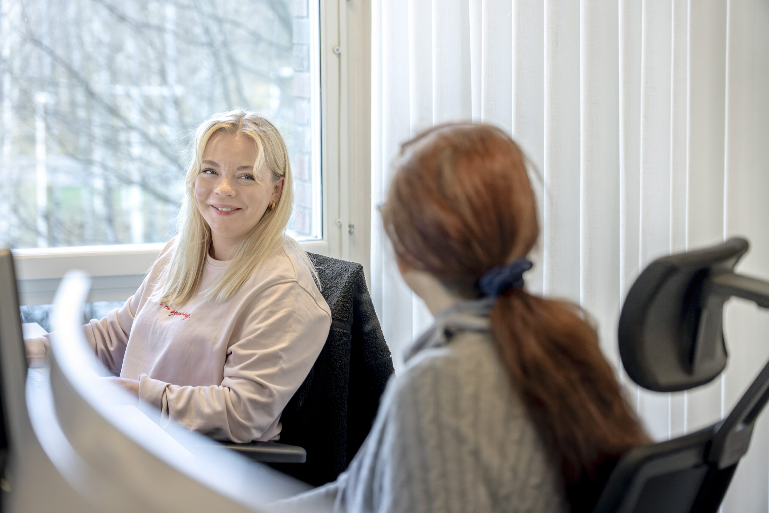 Två anställda vid NetNordic som sitter i kontorsmiljö och ler mot varandra.